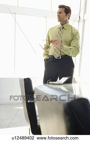 Stock Image - Business man standing in conference room. Fotosearch