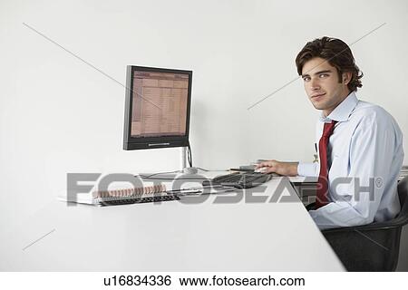 Business man using computer, sitting at office desk, side view, portrait View Large Photo Image Stock Photograph - Business man using computer, sitting at office desk, side view, portrait. Fotosearch