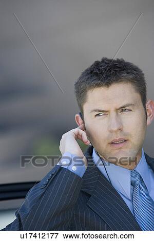 Business man wearing earpiece, outdoors View Large Photo Image Stock Photo - Business man wearing earpiece, outdoors. Fotosearch