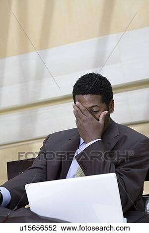 Stock Image - Business man with head in hands. Fotosearch