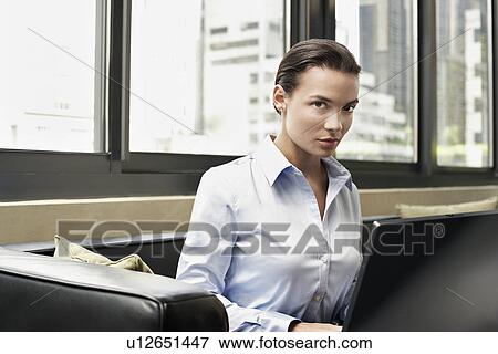 Business woman sitting on sofa using lap top View Large Photo Image Stock Photo - Business woman sitting on sofa using lap top. Fotosearch