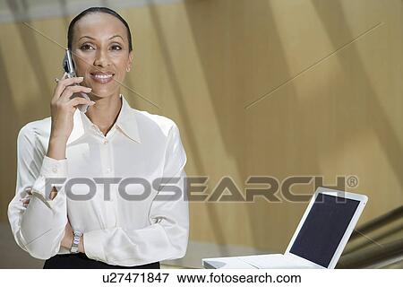 Business woman using mobile phone in office View Large Photo Image Stock Photo - Business woman using mobile phone in office. Fotosearch