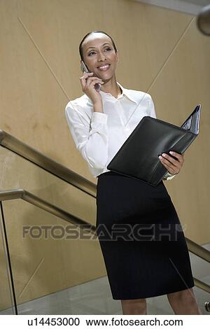 Stock Image - Business woman using mobile phone on stairs. Fotosearch