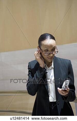 Picture - Business woman using mobile phone, indoors. Fotosearch