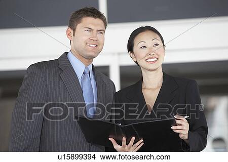 Businessman and Businesswoman holding folder in office, half length View Large Photo Image Picture - Businessman and Businesswoman holding folder in office, half length. Fotosearch