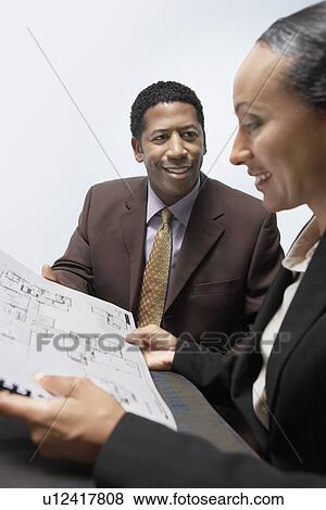 Businessman and Businesswoman Looking at Plans in Office View Large Photo Image Stock Photo - Businessman and Businesswoman Looking at Plans in Office. Fotosearch