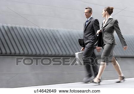 Stock Photo - Businessman and businesswoman walking outside building. Fotosearch