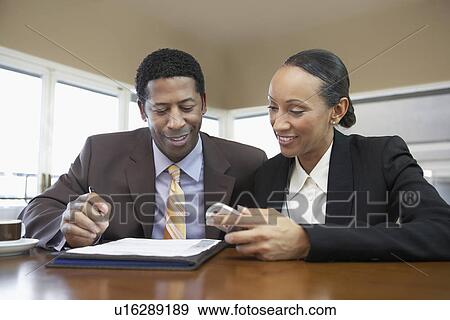 Stock Photo - Businessman and Businesswoman with file and cell phone in office. Fotosearch
