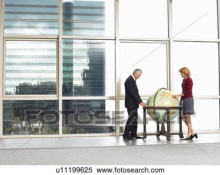 Businessman and woman studying large globe in office View Large Photo Image Stock Photography - Businessman and woman studying large globe in office. Fotosearch