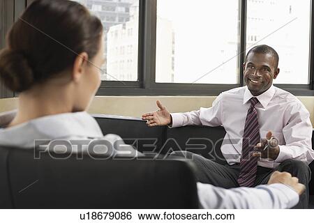 Businessman and woman talking sitting on sofas View Large Photo Image Stock Photograph - Businessman and woman talking sitting on sofas. Fotosearch