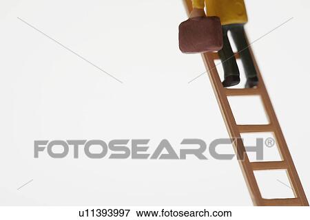 Stock Photo - Businessman figurine climbing ladder, low section. Fotosearch