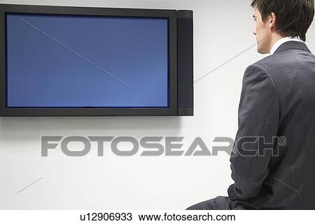 Stock Image - Businessman Looking at Flat Panel Television. Fotosearch