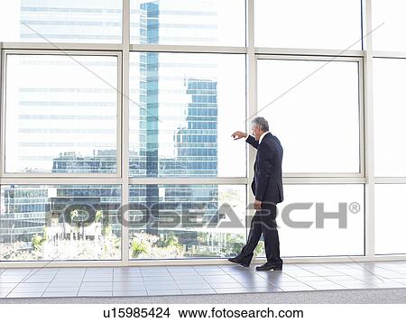 Picture - Businessman looking out of office window. Fotosearch