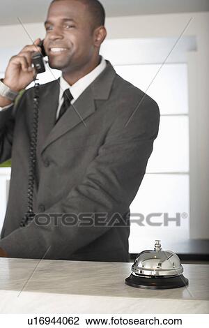 Businessman on phone at hotel reception desk View Large Photo Image Stock Image - Businessman on phone at hotel reception desk. Fotosearch
