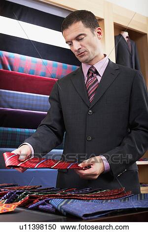 Businessman selecting tie in clothes store View Large Photo Image Stock Image - Businessman selecting tie in clothes store. Fotosearch