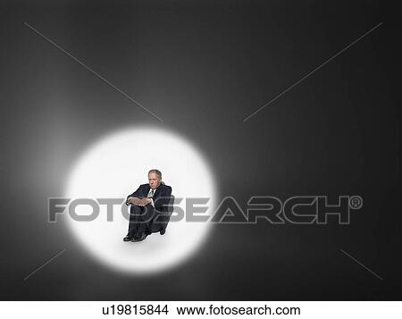 Businessman sitting in spotlight View Large Photo Image Picture - Businessman sitting in spotlight. Fotosearch