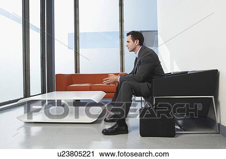 Stock Image - Businessman sitting in waiting room. Fotosearch