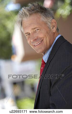 Stock Image - Businessman smiling outside, half length. Fotosearch