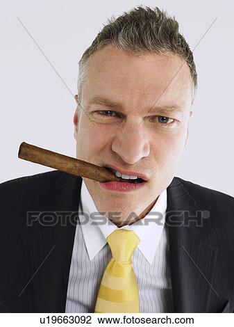 Businessman smoking cigar in studio View Large Photo Image Stock Image - Businessman smoking cigar in studio. Fotosearch