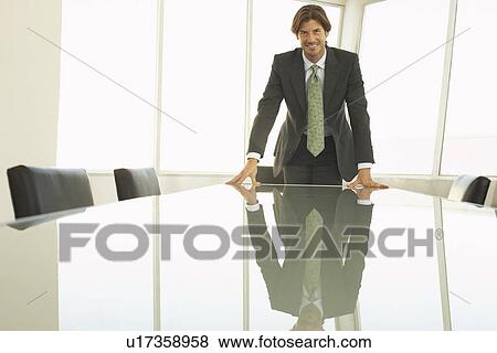 Stock Photo - Businessman standing at conference table, portrait. Fotosearch
