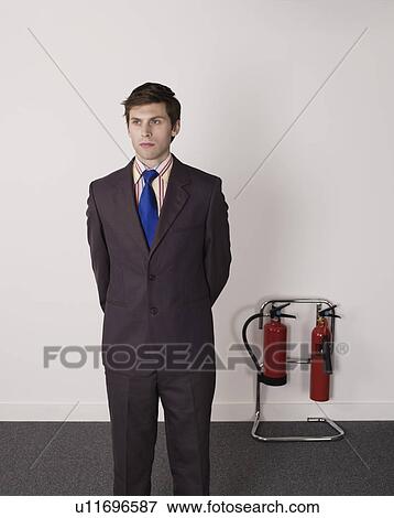 Businessman standing near fire extinguisher View Large Photo Image Stock Photo - Businessman standing near fire extinguisher. Fotosearch