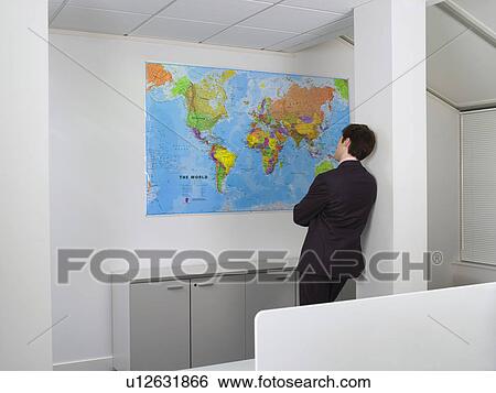 Businessman studying world map in office View Large Photo Image Stock Photograph - Businessman studying world map in office. Fotosearch