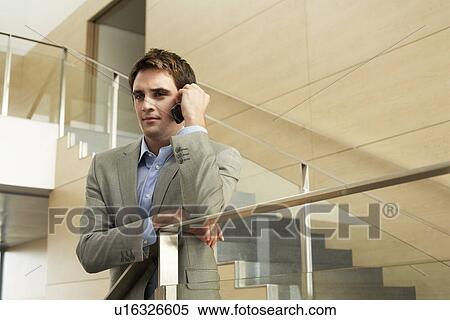 Stock Photography - Businessman talking on cell phone standing on stairs. Fotosearch