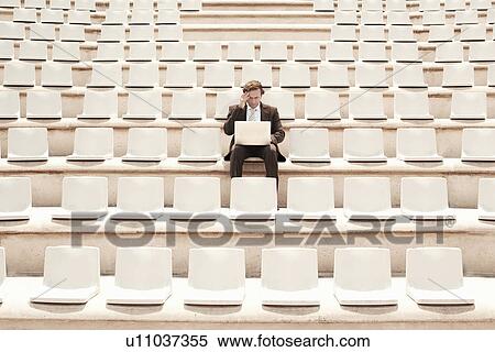 Businessman Using Laptop in Auditorium, front view. View Large Photo Image Stock Photography - Businessman Using Laptop in Auditorium, front view.. Fotosearch