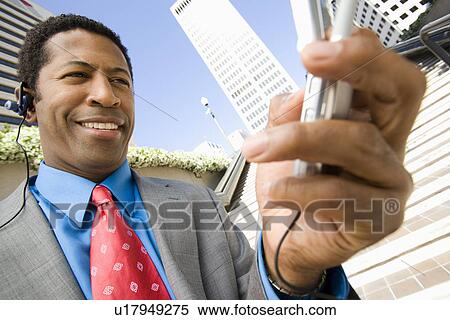Stock Photography - Businessman using mobile, outdoors, smiling. Fotosearch