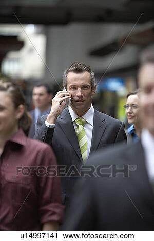 Businessman using mobile phone among crowd in station View Large Photo Image Stock Image - Businessman using mobile phone among crowd in station. Fotosearch