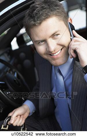Stock Image - Businessman Using mobile Phone in car, smiling, half-length. Fotosearch