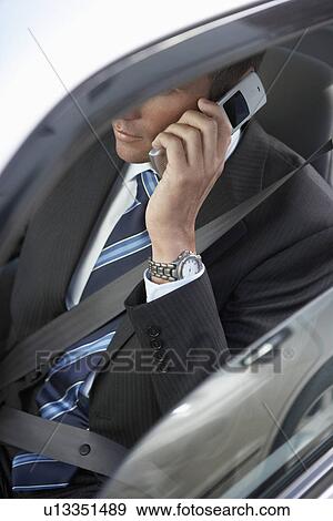 Stock Photo - Businessman using mobile phone in car, mid section, elevated view. Fotosearch