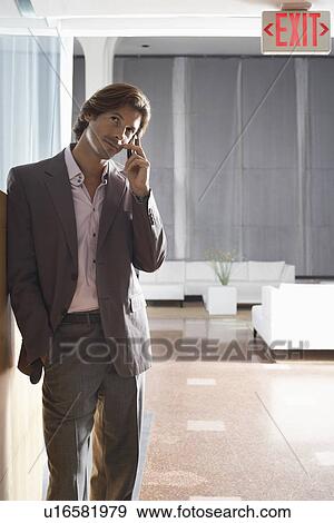 Stock Photo - Businessman using mobile phone in lobby. Fotosearch