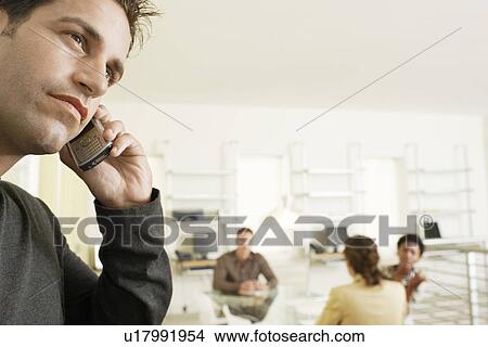 Picture - Businessman using mobile phone in office. Fotosearch