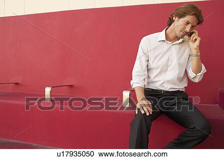 Businessman using mobile phone on bench, indoors View Large Photo Image Stock Image - Businessman using mobile phone on bench, indoors. Fotosearch