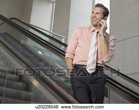 Businessman using mobile phone on escalator View Large Photo Image Stock Photo - Businessman using mobile phone on escalator. Fotosearch