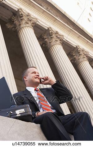 Stock Photography - Businessman using mobile phone outside courthouse. Fotosearch