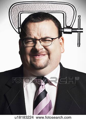 Picture - Businessman with head in vice, close-up. Fotosearch