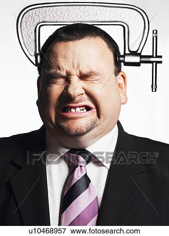 Stock Photo - Businessman with head in vice, close-up. Fotosearch
