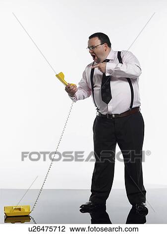 Stock Image - Businessman yelling at phone. Fotosearch