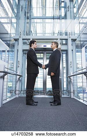 Businessmen shaking hands in office building View Large Photo Image Stock Photo - Businessmen shaking hands in office building. Fotosearch
