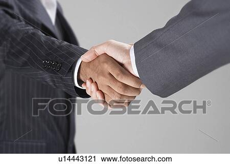 Stock Image - Businessmen Shaking Hands, mid-section. Fotosearch