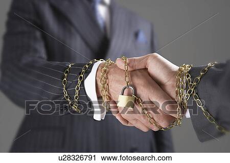 Businessmen shaking hands wrapped in gold chain with padlock, close-up of hands View Large Photo Image Stock Image - Businessmen shaking hands wrapped in gold chain with padlock, close-up of hands. Fotosearch