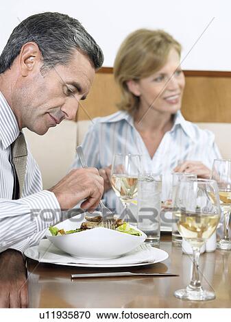 Stock Image - Businesspeople dining in restaurant. Fotosearch