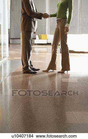 Picture - Businesspeople shaking hands, indoors, low section. Fotosearch