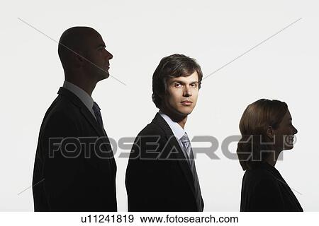 Stock Photo - Businesspeople standing in row, in height order, middle man facing camera in spotlight. Fotosearch