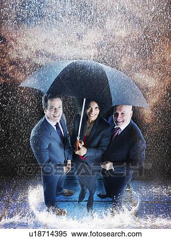Stock Photography - Businesspeople under one umbrella. Fotosearch