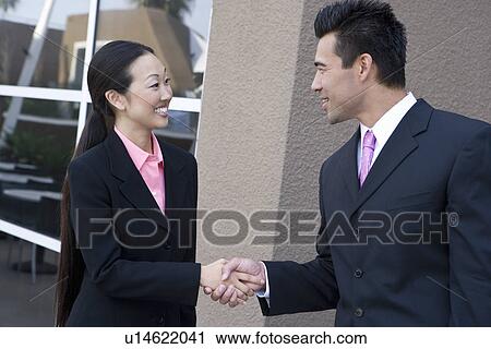 Stock Image - Businesswoman and businessman shaking hands. Fotosearch