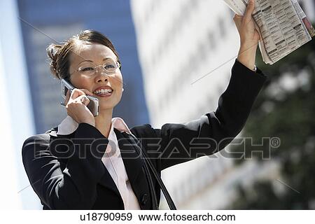 Stock Photo - Businesswoman Hailing Cab using Cell Phone. Fotosearch