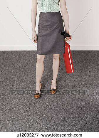 Businesswoman holding fire extinguisher, low section View Large Photo Image Stock Photo - Businesswoman holding fire extinguisher, low section. Fotosearch